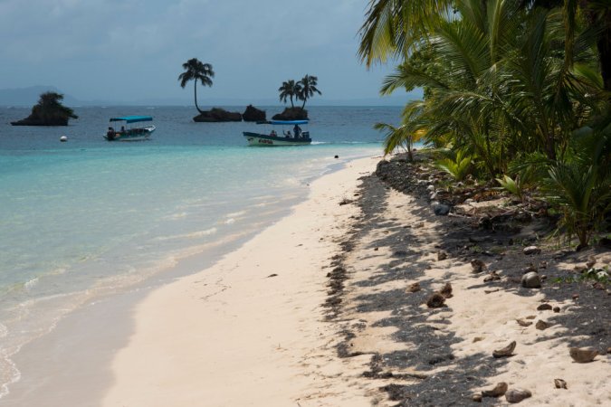 Island beach taken from the water surface with lush tropical vegetation, Bocas del Toro, Caribbean sea, Zapatillas Keys, Panama. Tropical beach island with leaning coconut tree and a boat, Caribbean sea, Zapatillas Keys. Zapatillas Keys These two beautiful islands are located on a coral platform that is defined, toward the open sea, by the breakers that are formed as the waves crash on the reef. (Photo by: Sergi Reboredo/VW PICS/Universal Images Group via Getty Images)