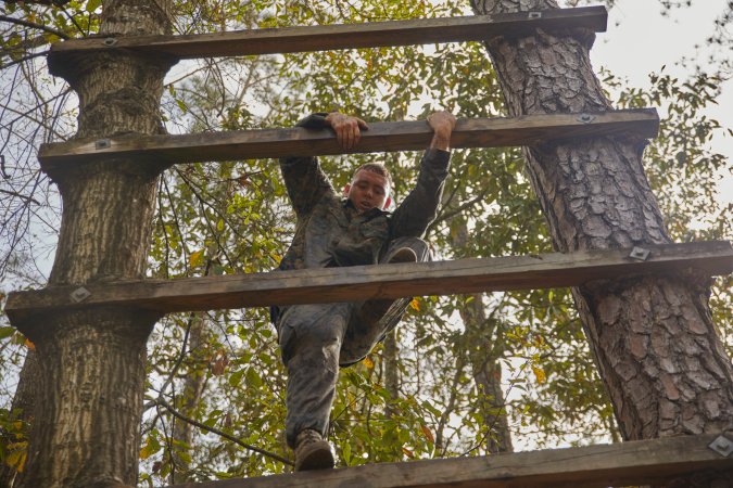 marine climbing an obstacle course ladder.