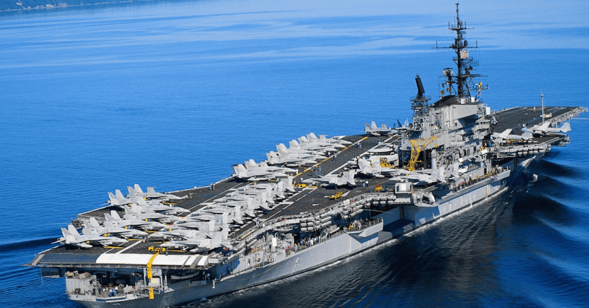 Navy aircraft carrier with planes on the deck floats through the ocean with people who were interested in joining the navy.