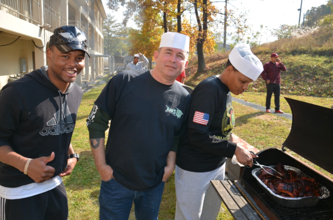 Three sailors grill ribs on a smoker