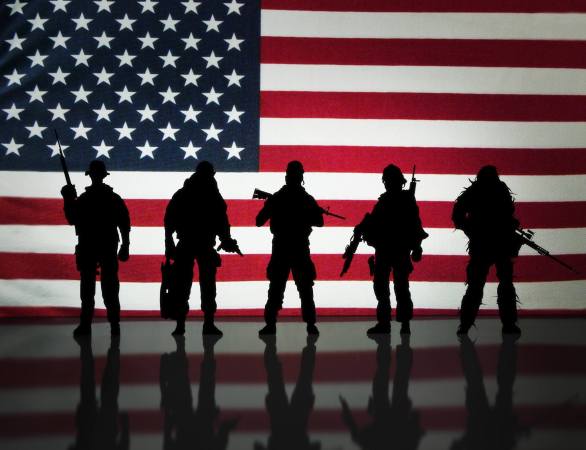 Soldiers stand in front of a flag