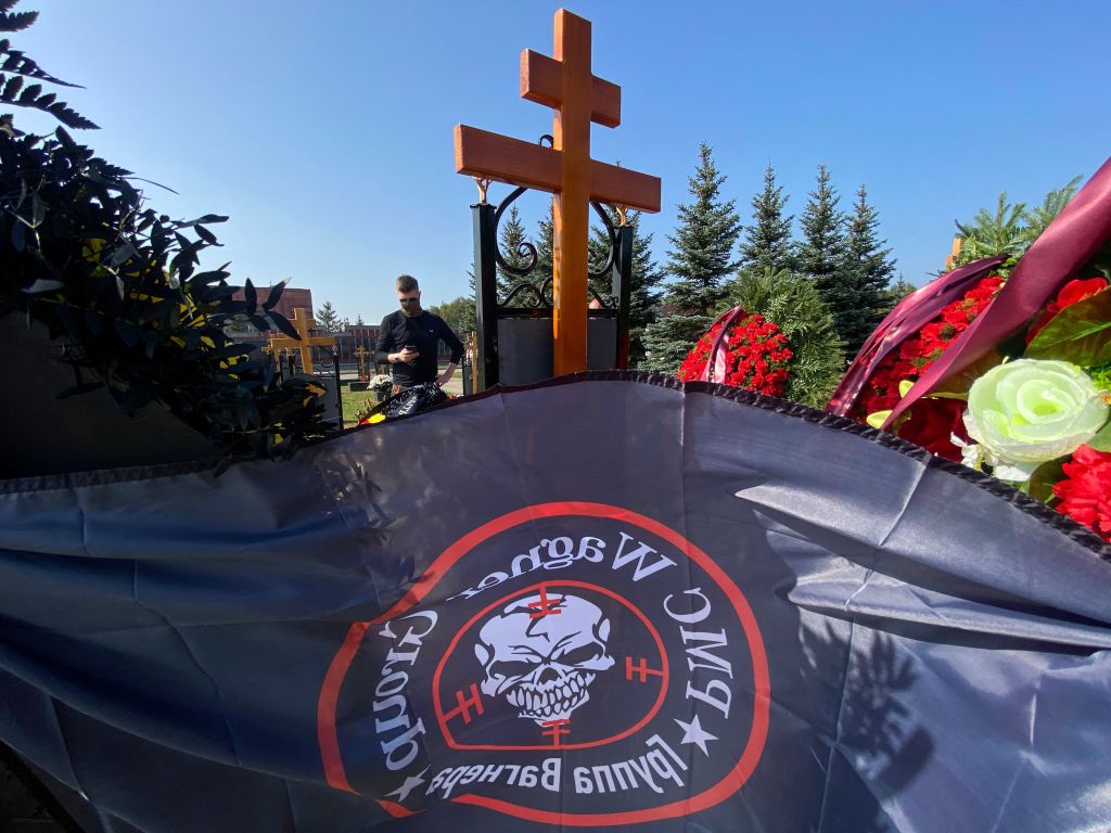 a mercenary flag flies in front of a cross