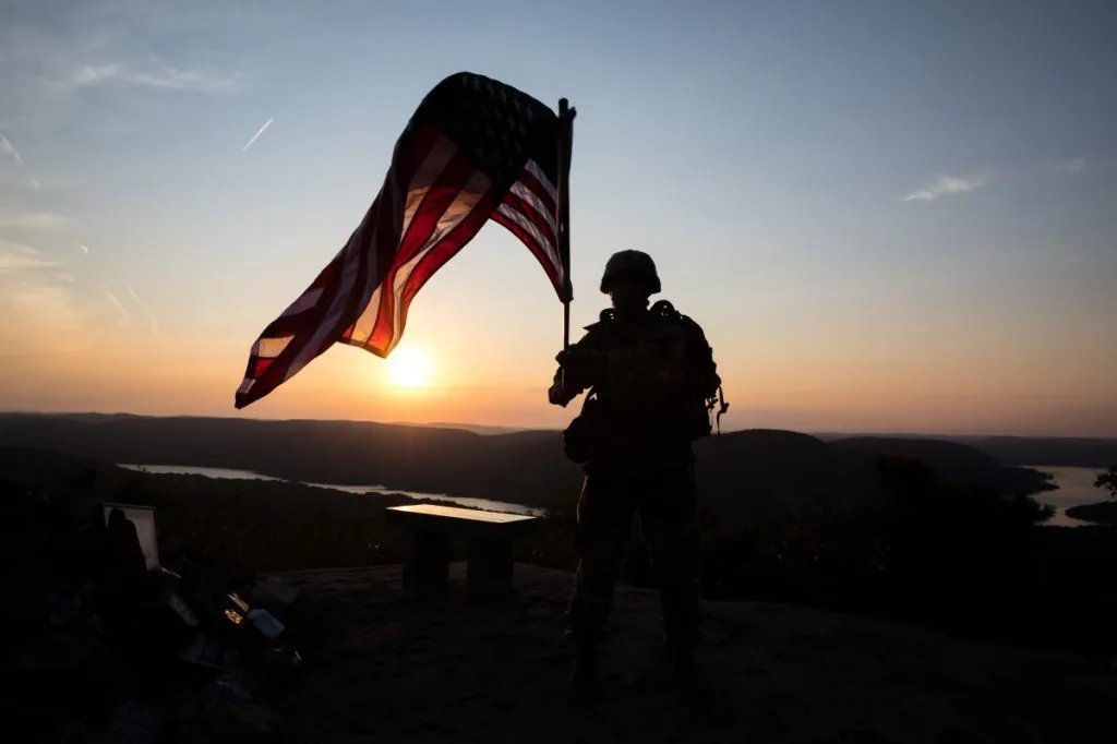 A Soldier waves an American flag at the top of the Trail of the Fallen, located right outside of West Point, Aug. 25, 2020. The Trail of the Fallen is a hiking trail memorializing fallen Soldiers. (U.S. Army photo by Michelle Eberhart)