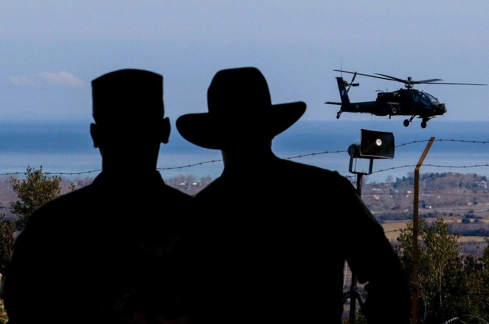 silhouettes of two marines watching helicopter