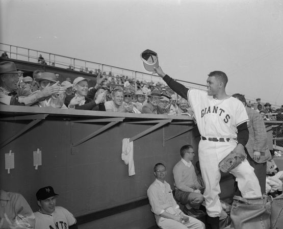 (Original Caption) New York Giant's centerfielder Willie Mays waves to the crowd form the dugout after he arrived for Spring training at Phoenix, as shown here. Willie flew from his Army camp in Virginia, released after serving almost two years in the Army.