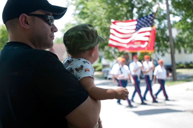 A dad holds a baby at a 4th of July parade