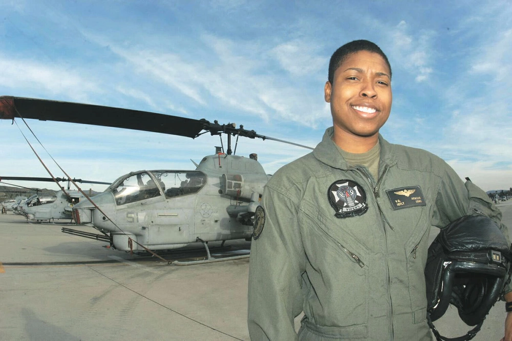 A female pilot stands in front of her helicopter