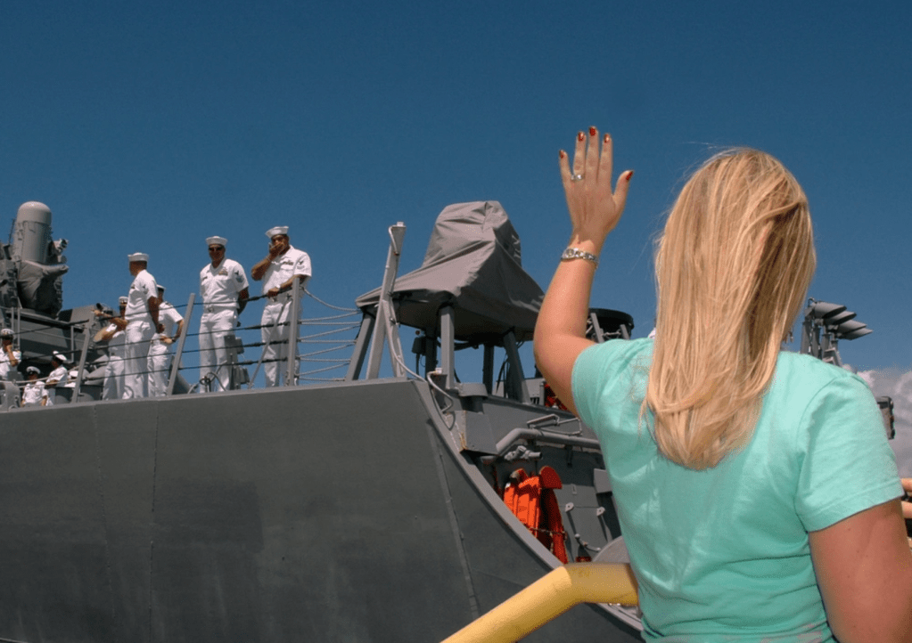 woman waves goodbye to ship