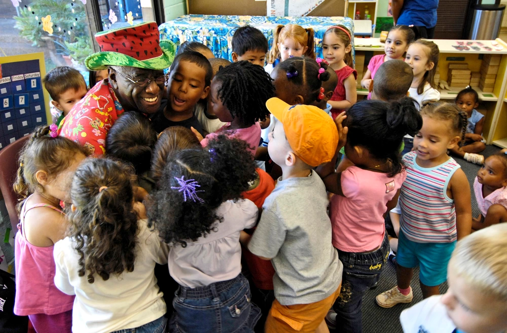 Wally Amos receives hugs from children at the Child Development Center after reading to them Sept. 10 at Hickam Air Force Base, Hawaii. Amos is an actor, writer and original entrepreneur behind the Famous Amos cookie brand. He is an advocate of literacy and early childhood development, and served in the Air Force four years. He read to children as part of Air Force week Honolulu. (U.S. Air Force photo/Tech. Sgt. Shane A. Cuomo)