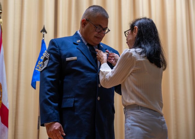 Vilma Perez pins an award on her husband, retired Chief Master Sgt. Ramon Perez, during his retirement ceremony at MacDill Air Force Base, Florida, March 2, 2024. Perez retired after 36 years of service. (U.S. Air National Guard photo by Senior Airman Brooke Keisler)