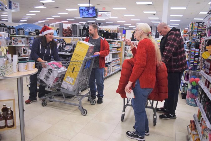 Steven Stanislow, second from left, gets help loading his shopping cart Dec. 21 during the Fort Riley, Kansas, Main Exchange $3,000 shopping spree. Stanislow, medically retired in 1999, was chosen as one of 40 winners, worldwide, and used the time to shop for family and friends before the Christmas holiday.