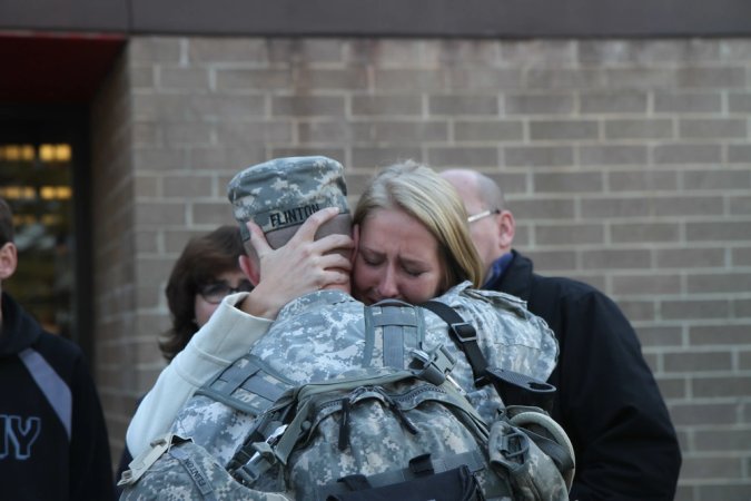 First Lt. Korey R. Flinton, native of Leesburg, Va., and executive officer, Bravo Company, 50th Signal Battalion (Expeditionary), 35th Signal Brigade (Theater Tactical), is hugged goodbye by his wife Courtney J. Flinton before boarding a bus at the 50th ESB headquarters, Fort Bragg, N.C., Nov. 10, and beginning his journey to Monrovia, Liberia, where he will add his signal expertise to the battle to contain the Ebola virus outbreak. (U.S. Army photo by Staff Sgt. Ashley M. Armstrong, 35th Signal Brigade (Theater Tactical) Public Affairs/Released)