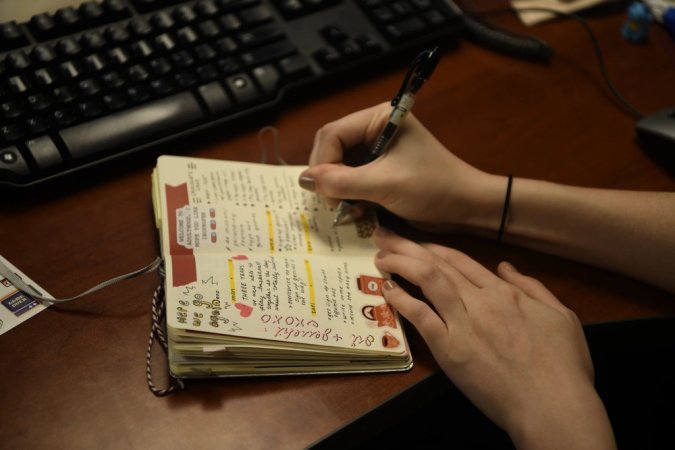 Senior Airman Oriana Beard writes a new bullet journal entry at her desk in the AFN Kunsan radio station, Kunsan Air Base, Republic of Korea, Feb. 13, 2020. Bullet Journaling is a method of writing a daily planner and including more artistic elements such as scrapbooking, sketching, painting or diary entries. (U.S. Air Force photo by Senior Airman Jerreht Harris)