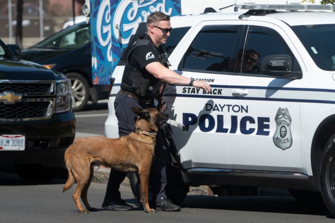 A Dayton police officer and his dog return to their vehicle after sweeping the Springfield City Hall grounds for explosives after bomb threats were made against buildings earlier in the day in Springfield, Ohio on September 12, 2024. A government building and school were evacuated after an alleged bomb threat Thursday in Springfield, Ohio, local media reported, rattling the small city at the heart of an anti-migrant conspiracy theory amplified by Donald Trump. Springfield has been thrust into the spotlight in recent days after an unfounded story of Haitian migrants eating pets went viral on social media, with the Republican ex-president and current White House candidate pushing the narrative despite it being debunked. (Photo by ROBERTO SCHMIDT / AFP) (Photo by ROBERTO SCHMIDT/AFP via Getty Images)