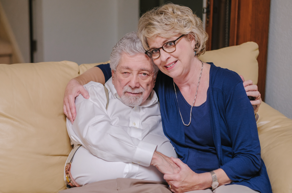 The author's mom and dad sit on a couch in an embrace