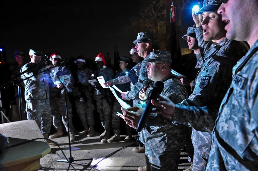 Soldiers based at Camp Ramadi, Iraq, join in the holiday festivities as they sing Christmas carols at the palm tree lighting ceremony, Dec. 5.