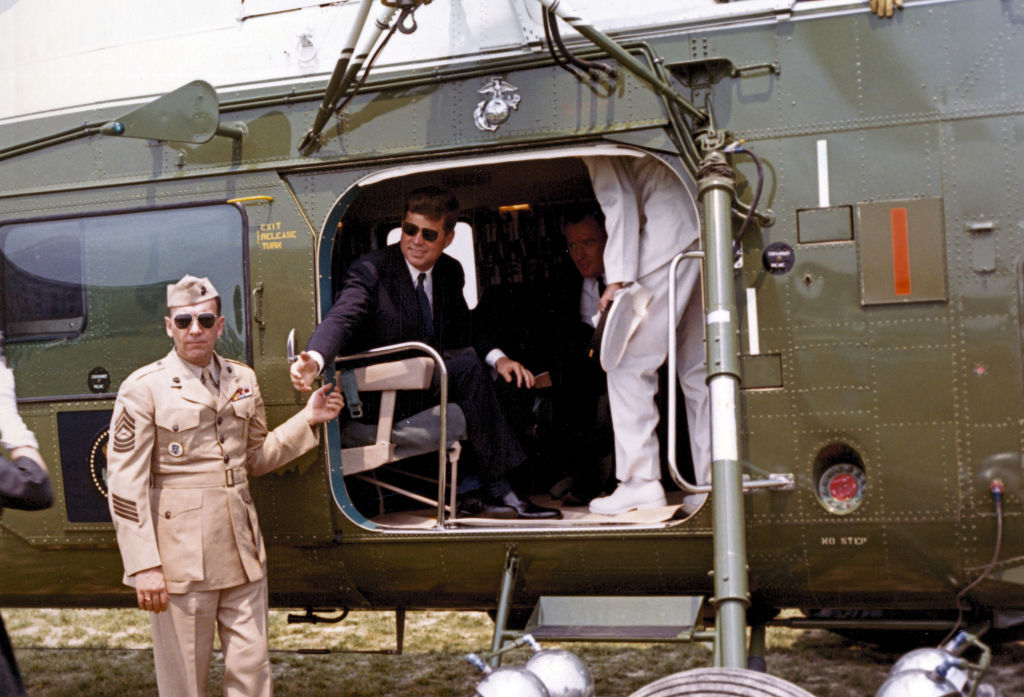 On the South Lawn of the White House, President John F Kennedy (1917 - 1963) sits with Undersecretary of the Navy Paul Fay (1918 - 2009) inside a helicopter as it prepares to fly to the commencement ceremony at the United States Naval Academy, Washington, DC, June 7, 1961. (Photo by National Archives/Interim Archives/Getty Images)