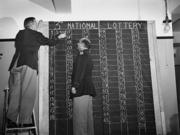 Colonel Arthur McDermott, New York City’s Director of Selective Service, watched by Major William Walsh as he chalks up the first four numbers drawn from the famous fish bowl in Washington on the '3rd National Lottery' board in the Selective Service Headquarters in New York City, New York, 17th March 1942. Watching him is . (Photo by Bettmann Archive/Getty Images)