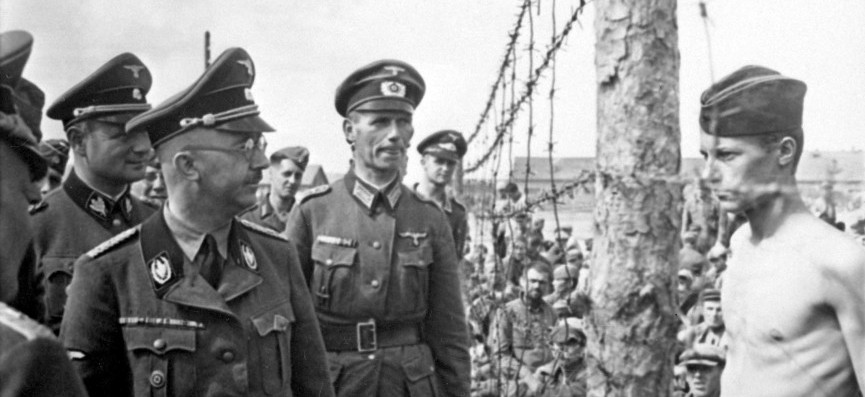 Officers stare at a POW through barbed wire
