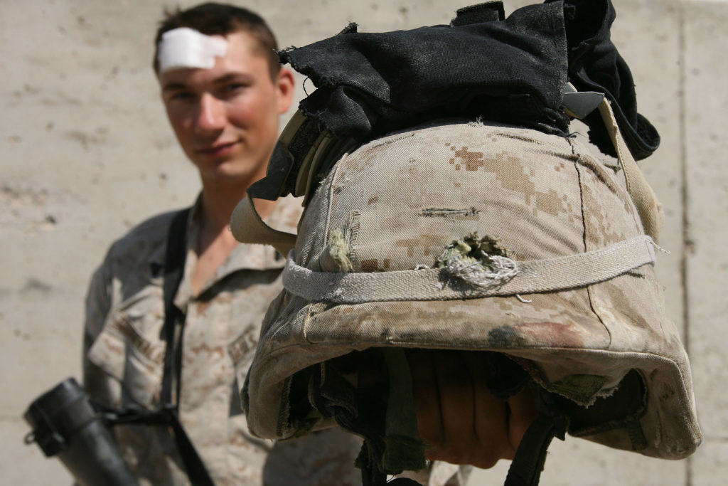 An assaultman holding the helmet that saved his lfe